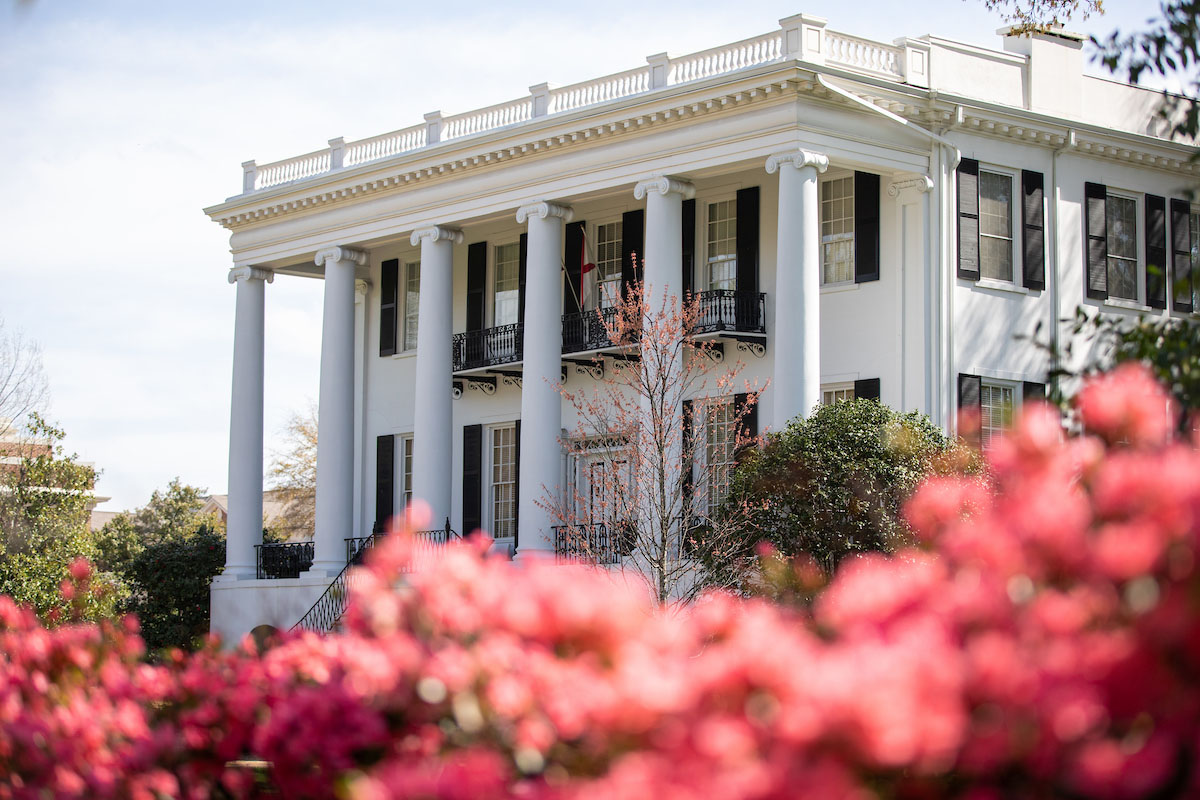 The President's Mansion on a sunny day with flowers around it.